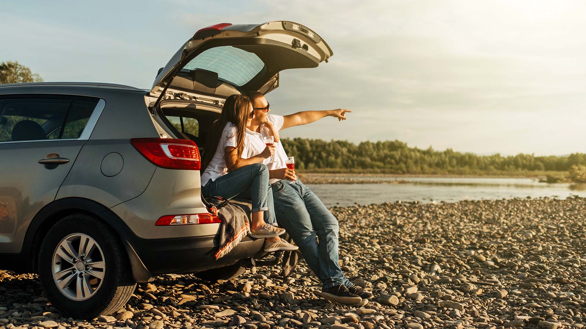  Couple assis sur le coffre d'un 4x4, admirant un coucher du soleil pendant un roadtvvv